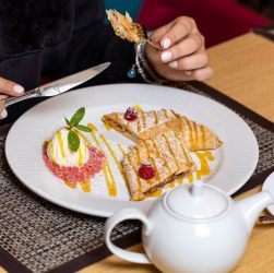 A close-up of a person enjoying a delicious dessert and tea in a cozy setting. — The Financial Perspective and Industry Knowl