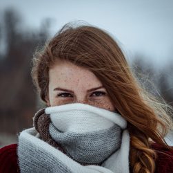 Portrait of a young woman with freckles, wrapped in a wool scarf, against a snowy winter background. — Why Choosing the Right
